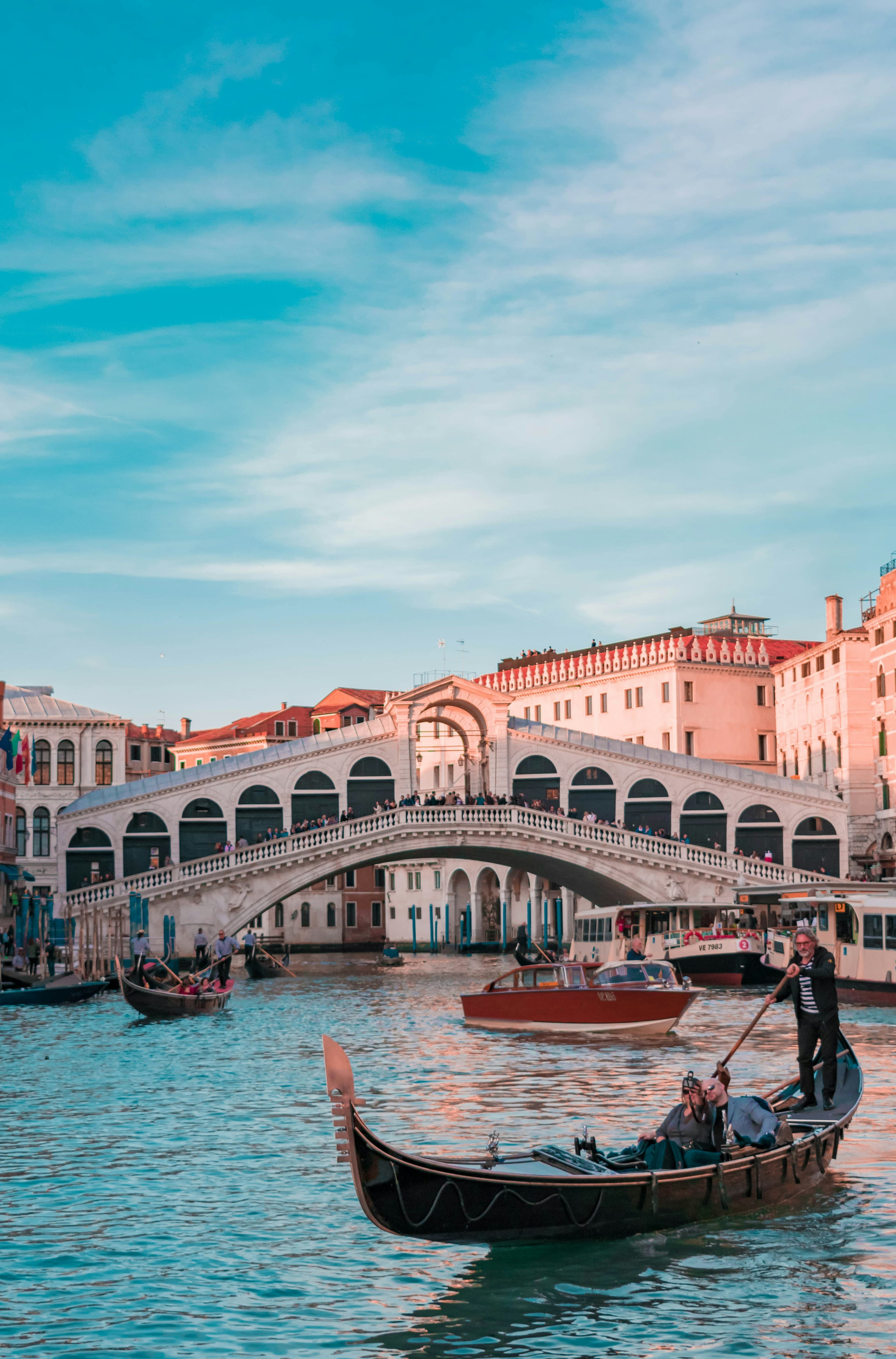 The Rialto bridge over a Venice canal on a clear day.